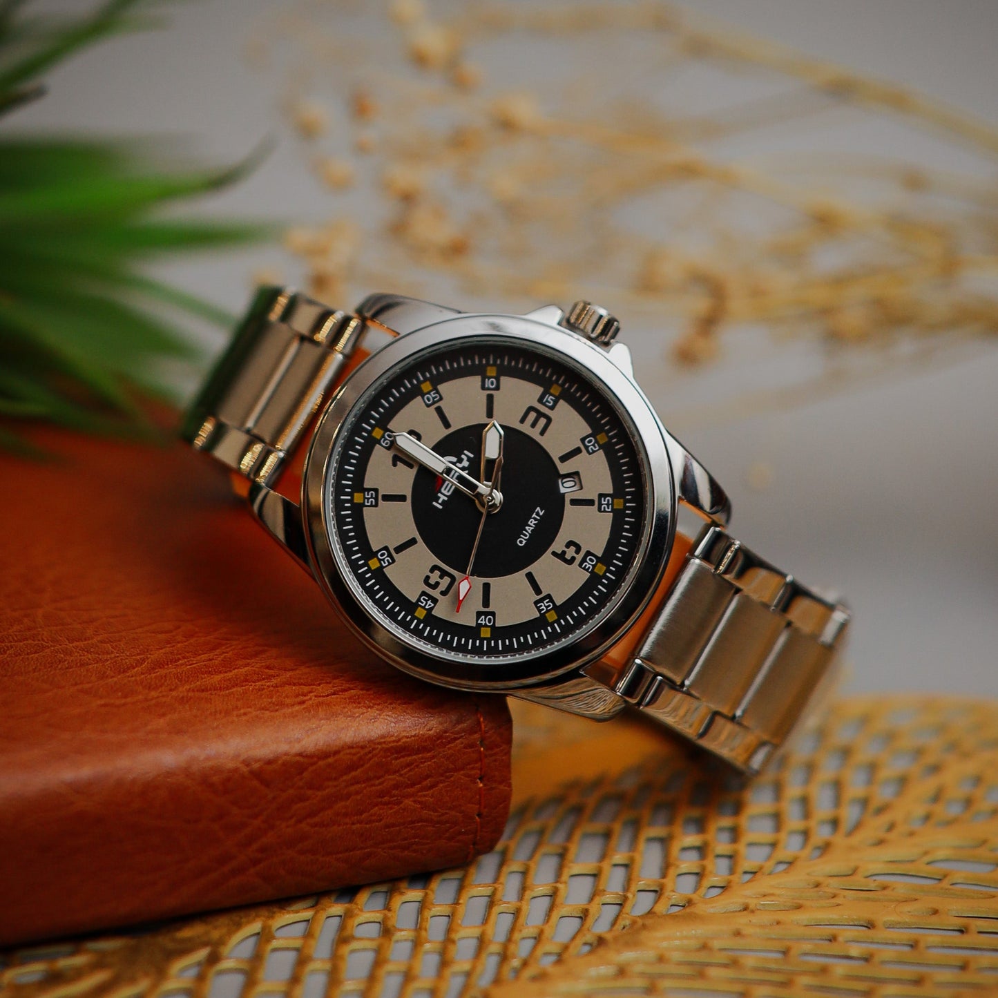 Wristwatch with black face and metal band on a textured surface