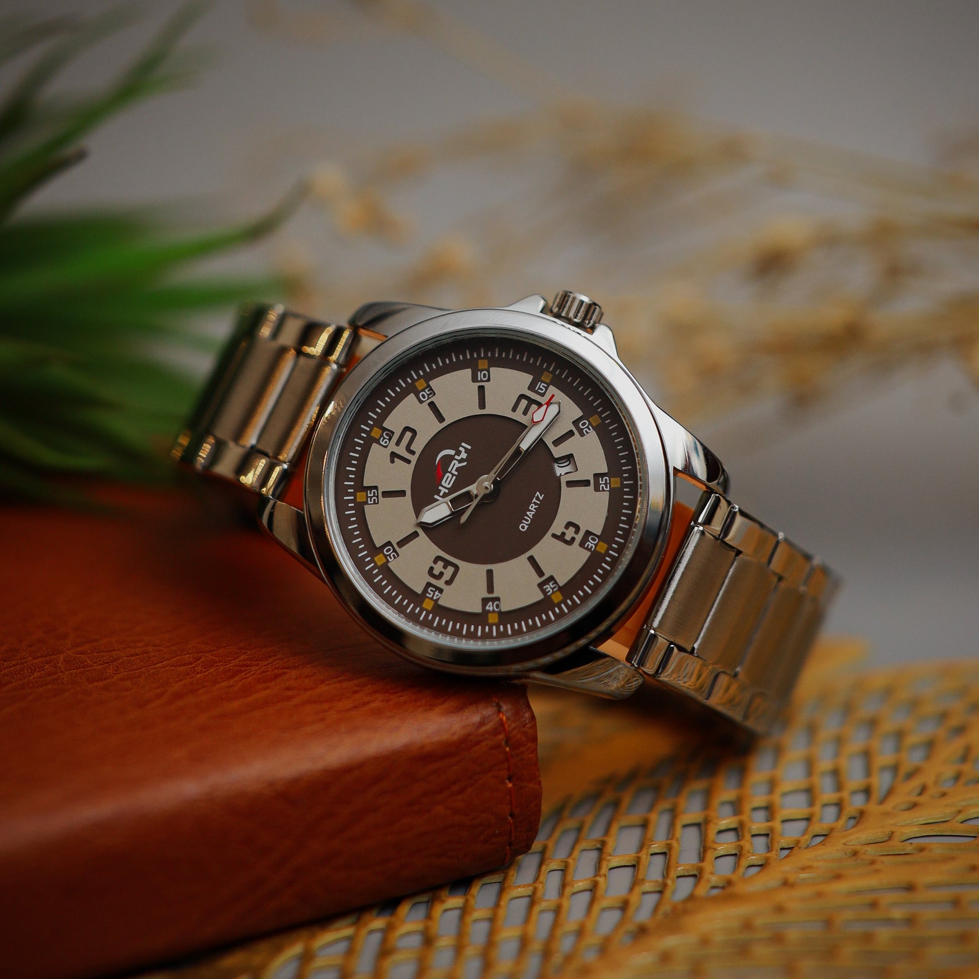 Wristwatch with Borwn face and metal band on a textured surface