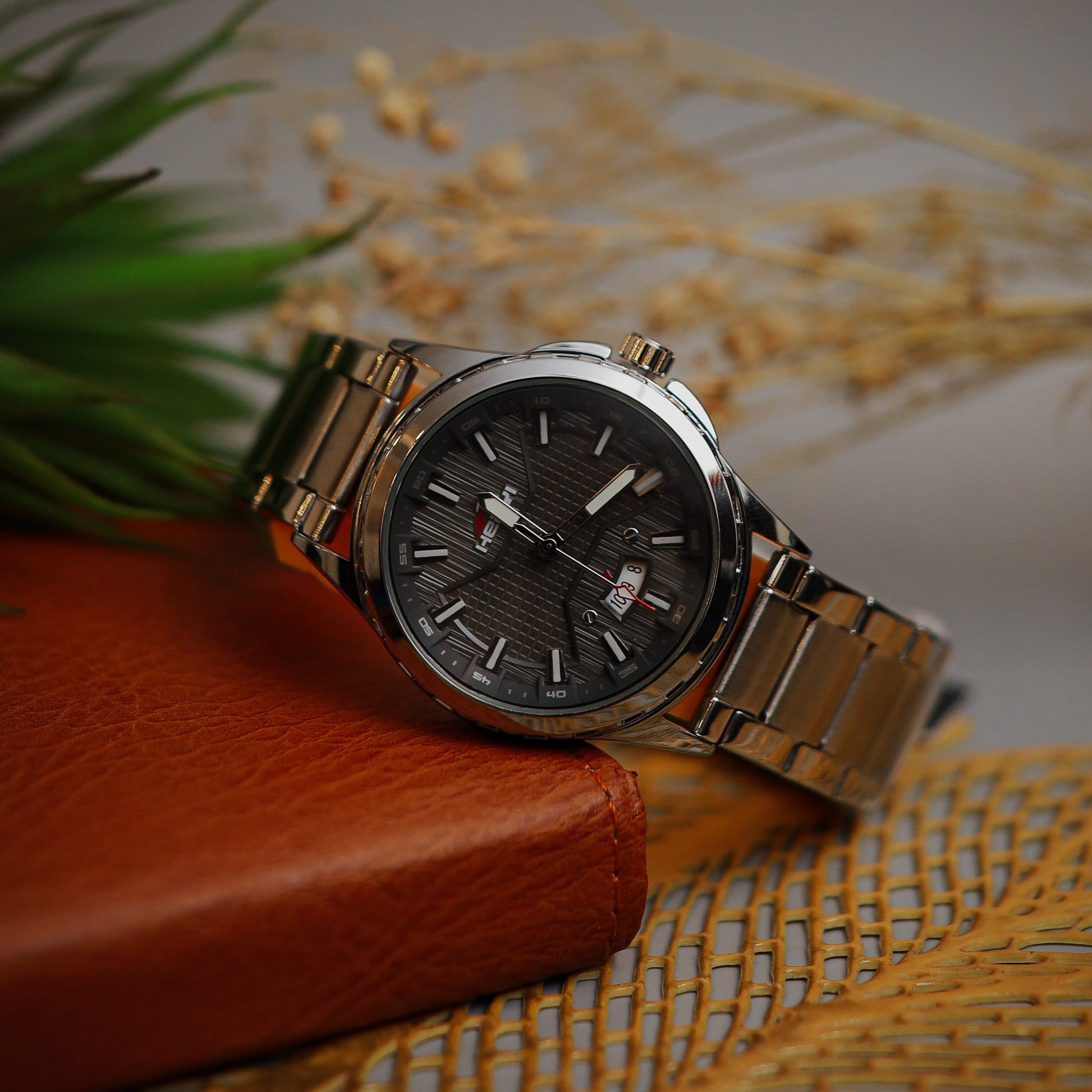 Silver watch with a black face on a textured surface
