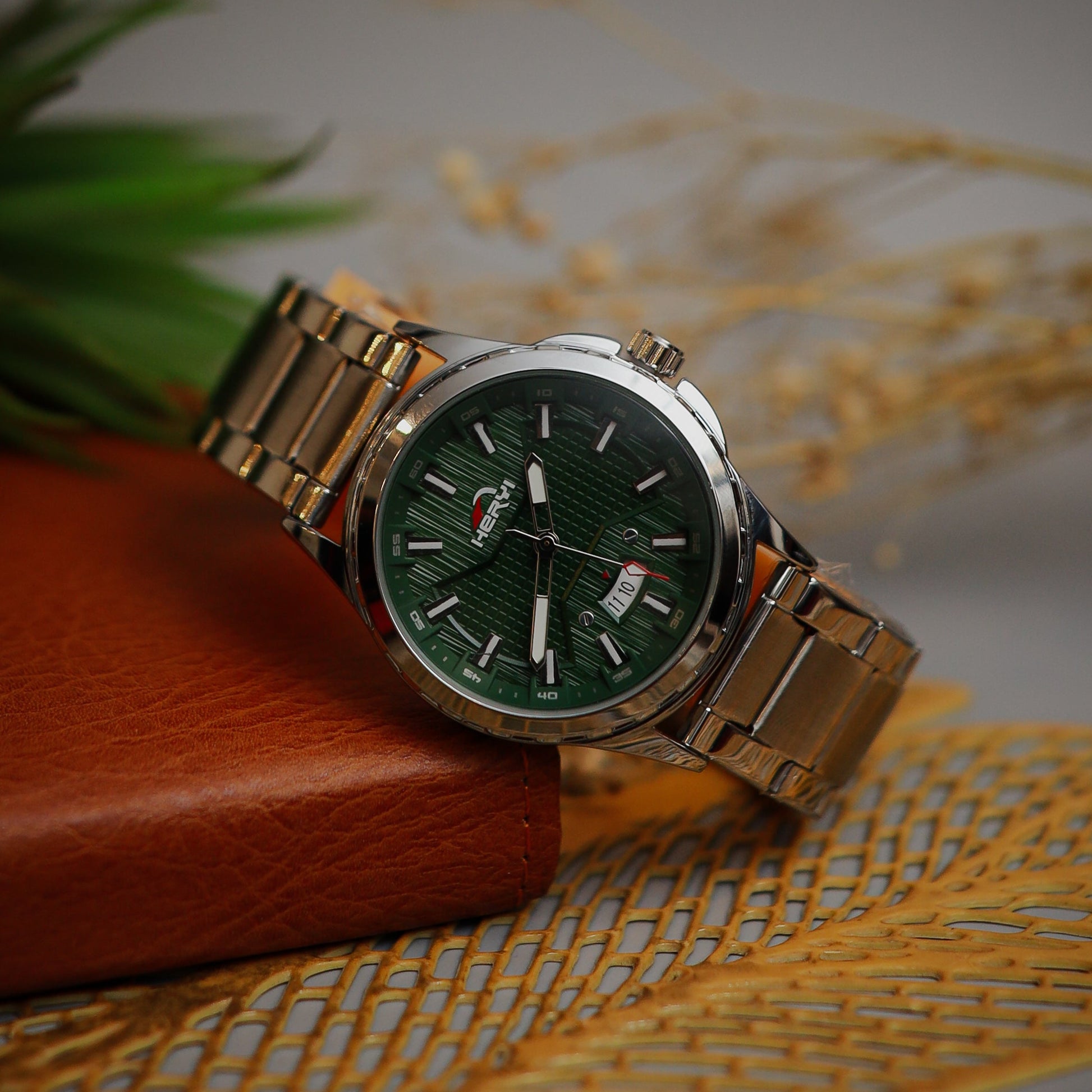 Silver watch with green dial on a textured surface